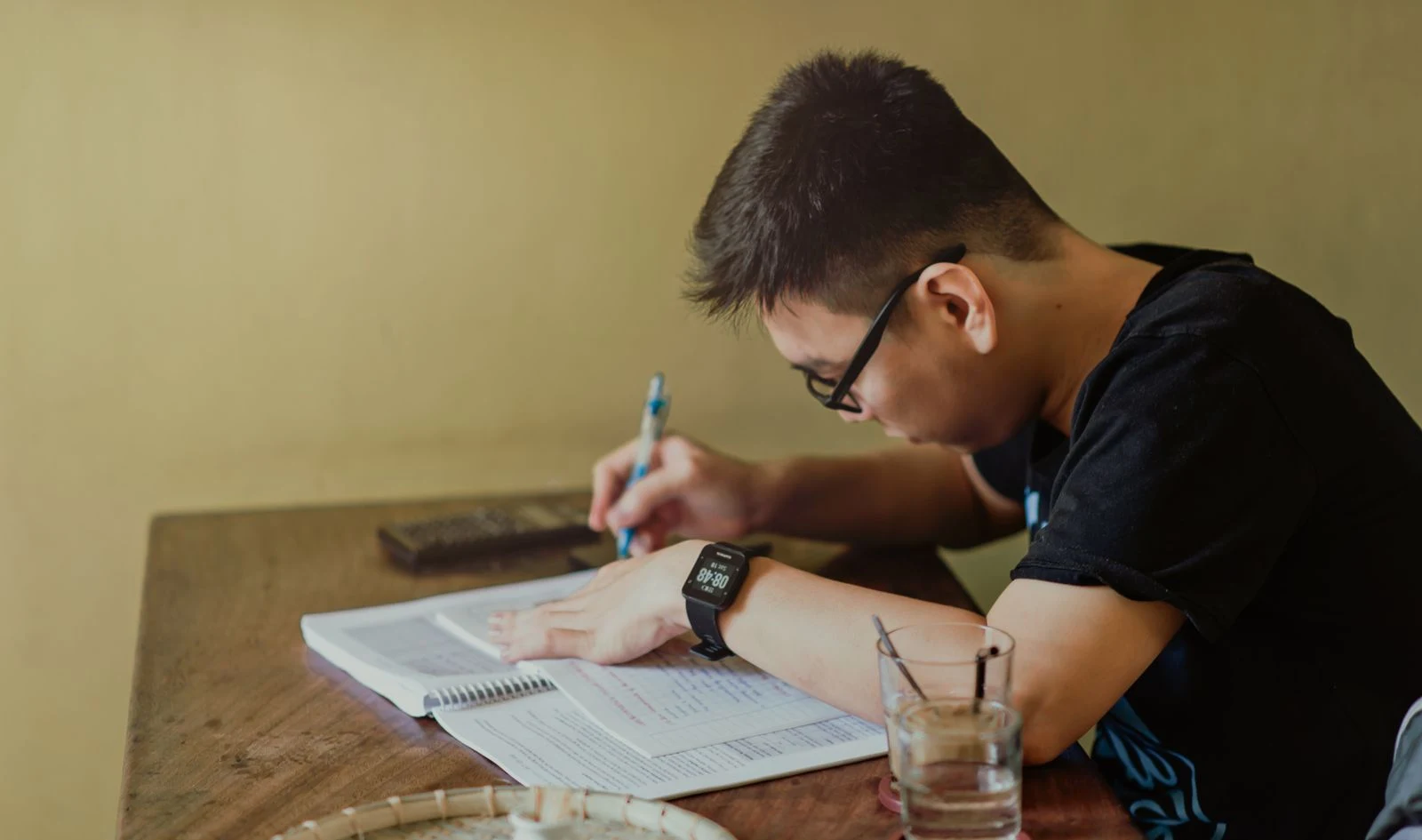 student at a desk completing financial aid paperwork with a calculator